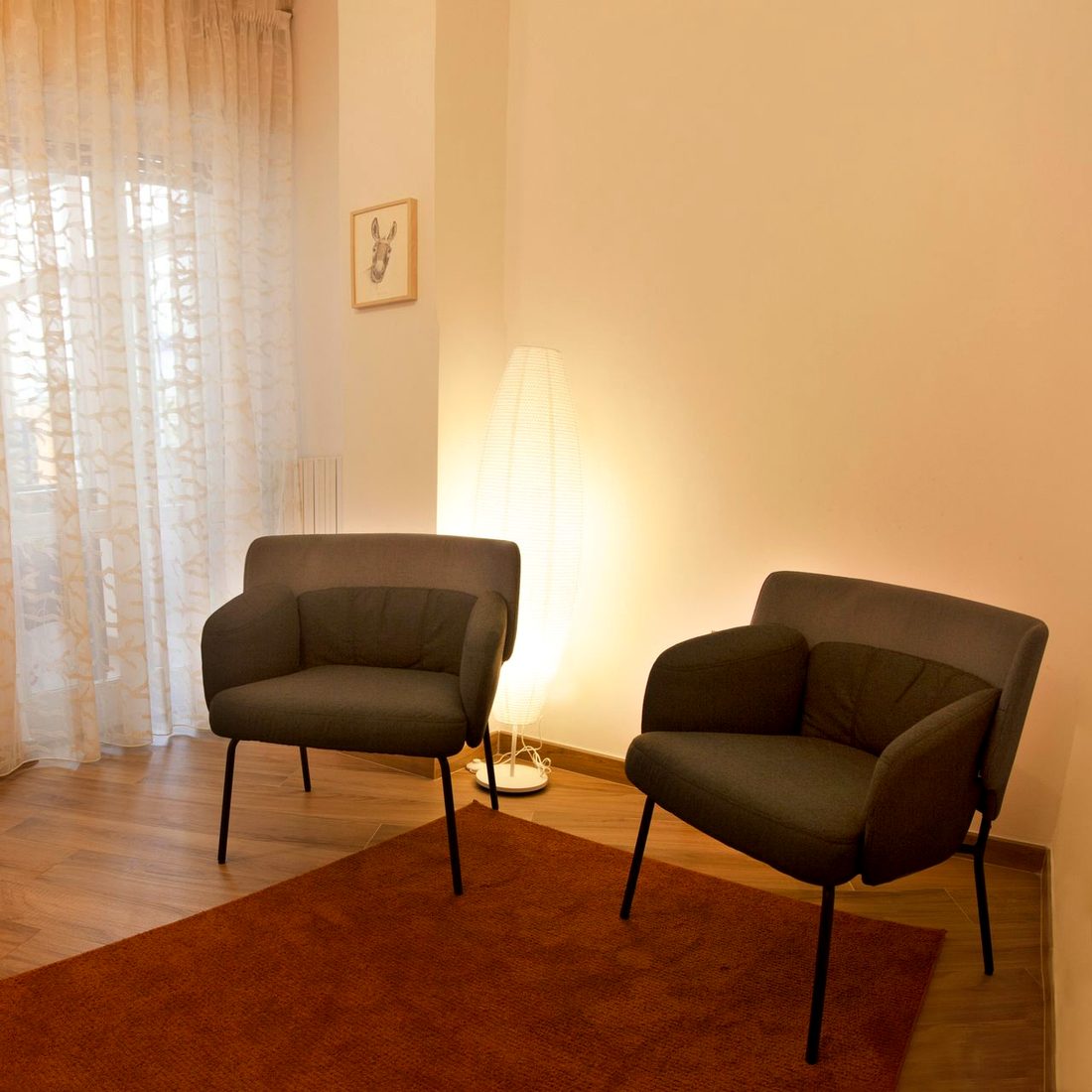 Lo studio a Fuorigrotta: poltrone verde salvia, tappeto terracotta e luce calda